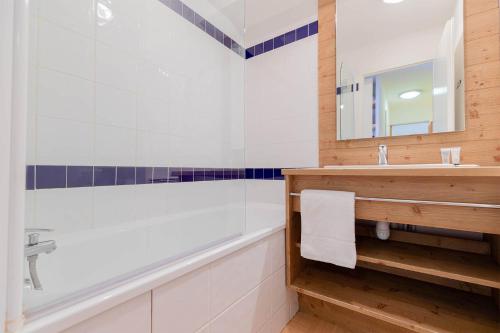 a bathroom with a tub and a sink at Madame Vacances Résidence Le Parc Des Airelles in Les Orres