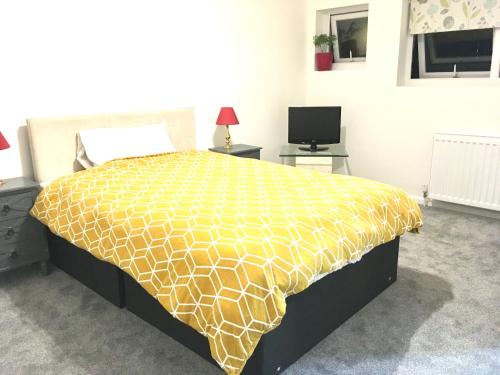 a bedroom with a bed with a yellow comforter at Grace Apartments - Living Stone 1 in Kent