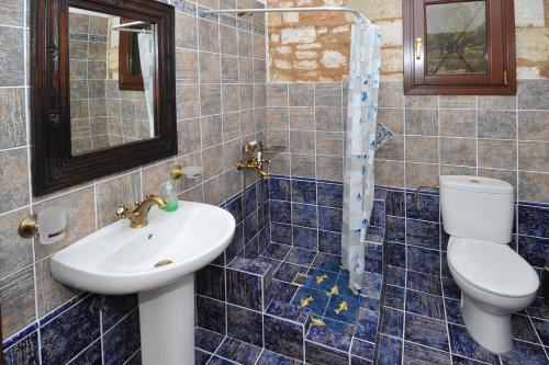 Baño de azulejos azules con aseo y lavamanos en VILLA KOUTSOYPIA STONE HOUSE, en Sami