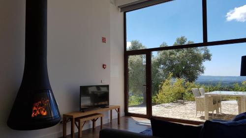 a living room with a fireplace and a large window at Casas do Monte de Roques in Vila de Punhe