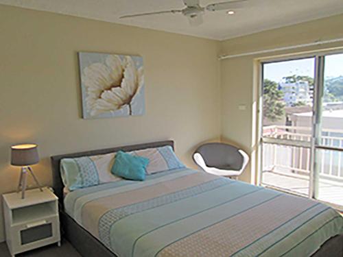 a bedroom with a bed with a view of a balcony at 15 'Kanangra', 39 Soldiers Point Road - fantastic unit right on the water in Soldiers Point