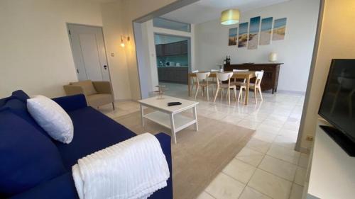 a living room with a blue couch and a table at Lusitania T2 Frente Mar em Quarteira in Quarteira