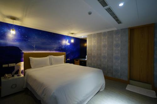 a bedroom with a large white bed with a blue wall at 浪琴Motel文創旅館 in Taichung