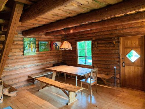 ein hölzernes Esszimmer mit einem Holztisch und Bänken in der Unterkunft Poilsio namelis Plateliuose in Plateliai