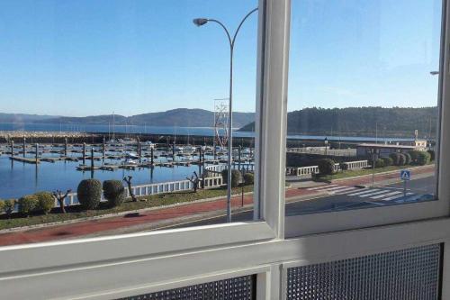 ventana con vistas a un puerto deportivo con barcos en Muxía Apartamento Malecón enfrente al puerto 4 personas, en Muxía