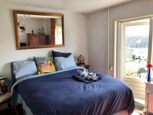 een slaapkamer met een blauw bed en een spiegel bij Art+bed and breakfast in 's-Graveland