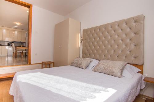 een slaapkamer met een groot bed met een groot hoofdeinde bij Apartmani VILLA KALINIC in Njivice