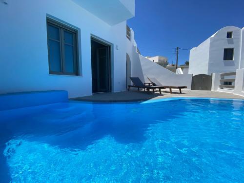 a blue swimming pool with a bench next to a house at Amphitrite Suites Santorini in Vóthon