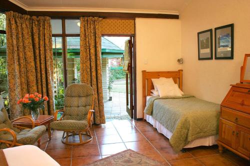 a bedroom with a bed and a chair and a window at The Palms Guesthouse in Nelspruit