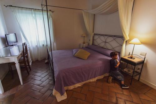 a young boy standing next to a bed in a bedroom at Valcastagno Relais in Sirolo