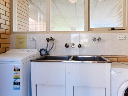 a kitchen with a sink and a washing machine at Little Hut 1 Spectacular Water Views NBN and Air Conditioned in Nelson Bay