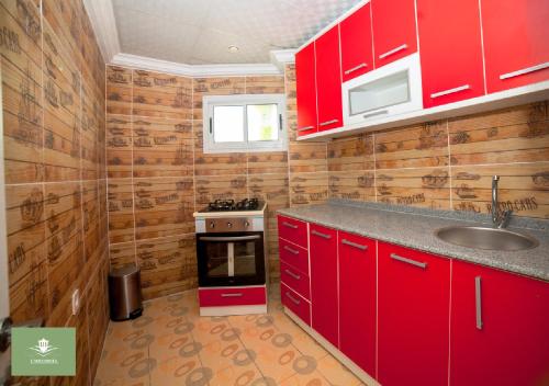a kitchen with red cabinets and a sink and a stove at United Hotel in Mbankomo