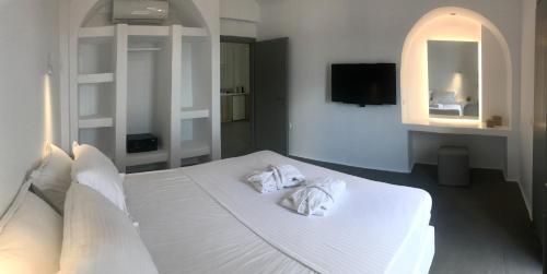 a bedroom with a white bed with towels on it at Amphitrite Suites Santorini in Vóthon