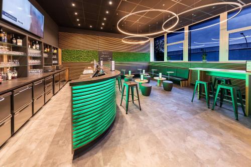 a restaurant with a bar with green stools at AMH Airport-Messe-Hotel Stuttgart in Filderstadt