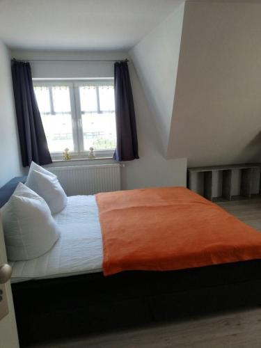 - une chambre avec un lit doté d'une couverture orange et d'une fenêtre dans l'établissement Ferienwohnung 313-1-R Stübchen, à Neddesitz