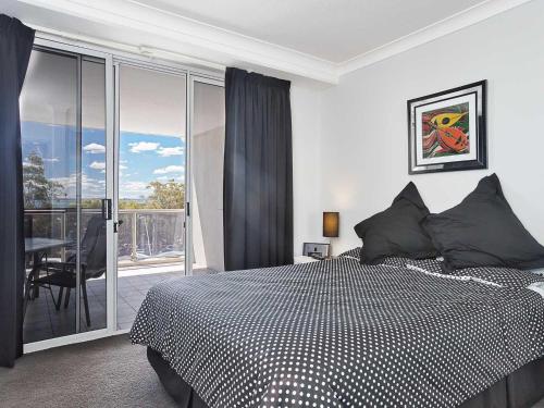 a bedroom with a bed and a balcony at Nelson Towers, 9,71a Victoria Parade - unit in the heart of Nelson Bay with water views, air conditioning and Wi-Fi in Nelson Bay