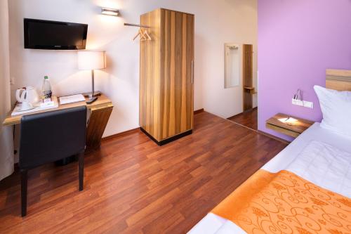 a hotel room with a bed and a desk with a phone at AMH Airport-Messe-Hotel Stuttgart in Filderstadt