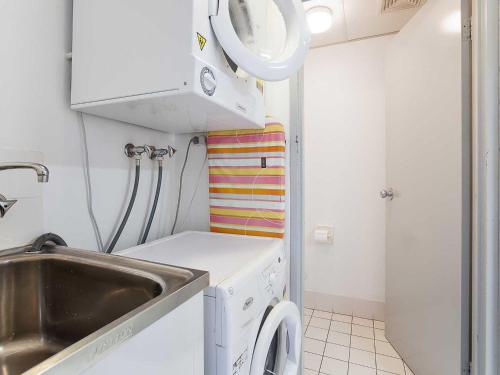 a small kitchen with a washing machine and a sink at Nelson Towers, 9,71a Victoria Parade - unit in the heart of Nelson Bay with water views, air conditioning and Wi-Fi in Nelson Bay