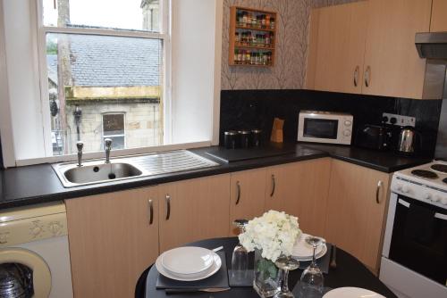a kitchen with a table with flowers on it at Kelpies Serviced Apartments McDonald- 2 Bedrooms in Falkirk