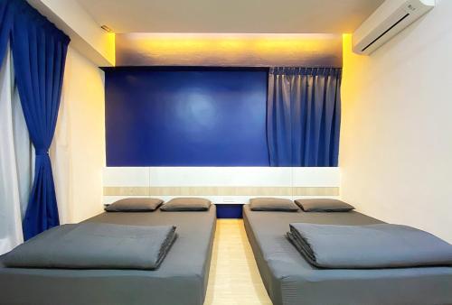 two beds in a room with blue curtains at Amadel Residence 爱媄德民宿 13 in Malacca