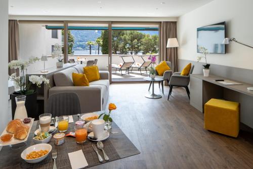 - un salon avec un canapé et une table avec de la nourriture dans l'établissement Hotel Lago Maggiore - Welcome!, à Locarno