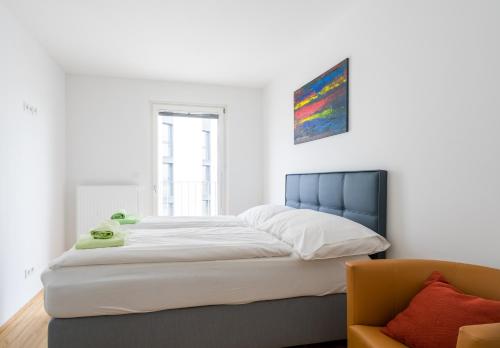 a bedroom with a large white bed and a chair at FeelGood Apartments GreenLiving | contactless check-in in Vienna
