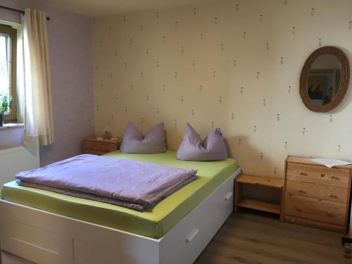 1 dormitorio con cama con almohadas moradas y espejo en Schlossblick Lauenstein, en Lauenstein