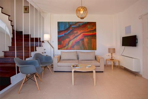 ein Wohnzimmer mit einem Sofa, einem Tisch und Stühlen in der Unterkunft Aegina Colors in Sfendoúrion