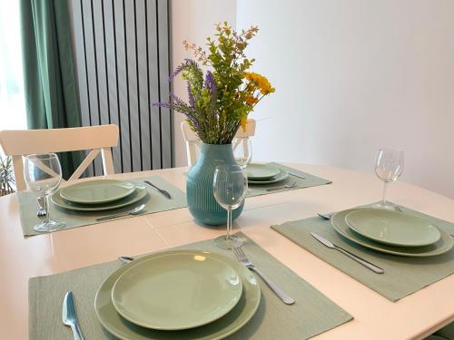 a table with plates and glasses and a vase with flowers at Deko Apartments Alezzi Beach Mamaia in Mamaia Nord