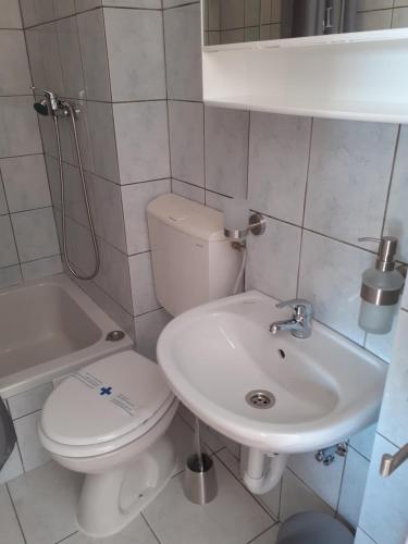 a white bathroom with a toilet and a sink at Room Domo in Senj