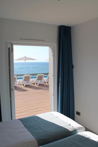 a bedroom with a bed and a view of the beach at Villa TURQUESA MAR in Cala en Forcat