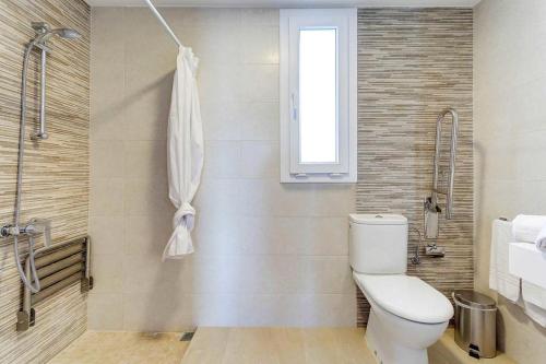 a bathroom with a toilet and a window at Villa TURQUESA MAR in Cala en Forcat