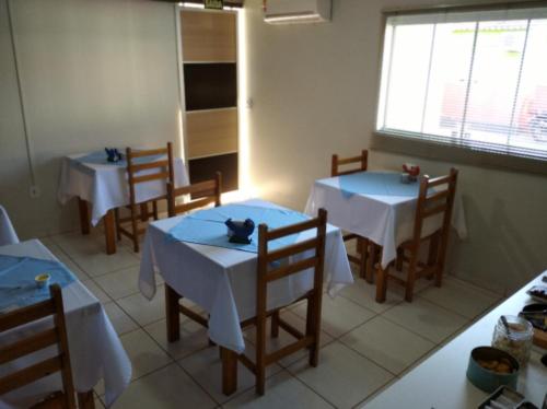 une salle à manger avec deux tables et des chaises avec des nappes blanches dans l'établissement Angelu's Hotel, à Nova Andradina