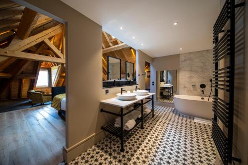 a bathroom with two sinks and a tub and a bedroom at Hôtel L'Incomparable by Les Etincelles in Tresserves