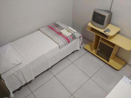 a small room with a bed and a small tv at Angelu's Hotel in Nova Andradina