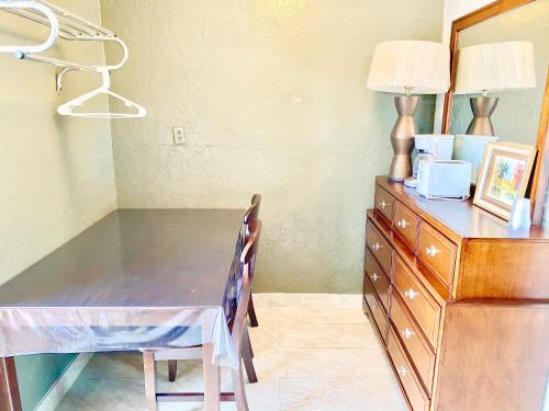 a dining room table with a dresser and a lamp at Glades Motel - Naples in Naples