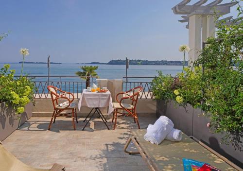 a table and chairs on a balcony with a view of the water at Hotel Du Lac Gardone Riviera in Gardone Riviera