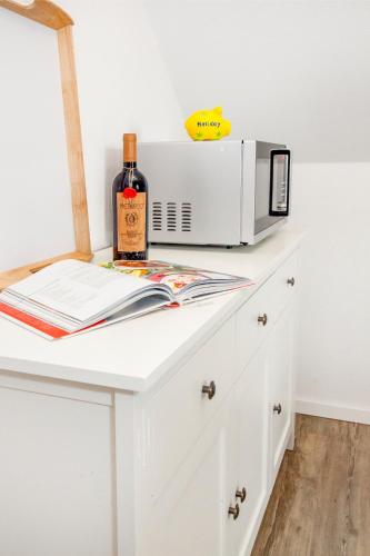 a white counter with a bottle of wine and a microwave at FeWo Nelly Marie Wohnung Nelly in Hademstorf