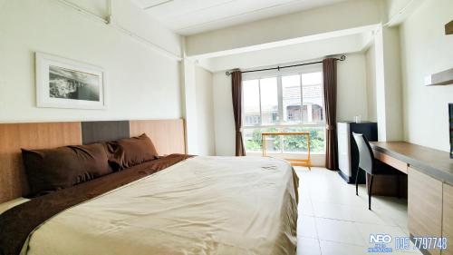 een slaapkamer met een bed, een bureau en een raam bij Neo km10โรงแรมที่พักใกล้สนามบินอู่ตะเภา แสมสาร สัตหีบ บ้านฉาง in Sattahip