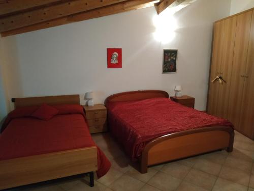 a bedroom with two beds and a red comforter at La Cort Di Nonna Rosa in Mori