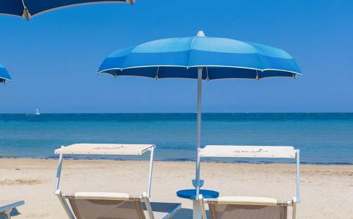 Dos sillas y una sombrilla en la playa en Hotel Atlantic Riviera Mare, en Misano Adriatico