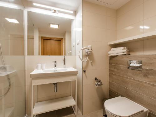 a bathroom with a sink and a toilet and a mirror at VacationClub – Seaside Park Apartament 644 in Kołobrzeg