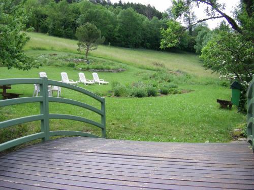 a wooden walkway with white chairs on a field at Hotel De l'Europe in Meyrueis