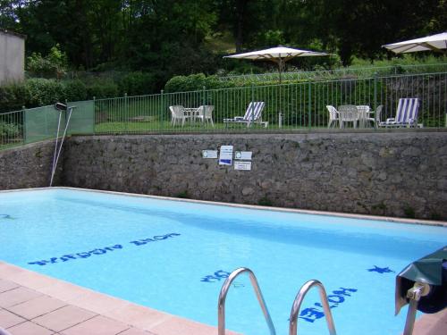 a swimming pool with chairs and a table and umbrella at Hotel De l'Europe in Meyrueis