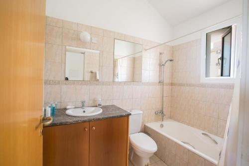 a bathroom with a sink and a tub and a toilet at Mandali Villa in Protaras
