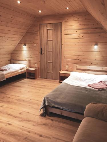 a bedroom with two beds in a wooden cabin at DOMKI STROME ZACISZE in Niedzica Zamek