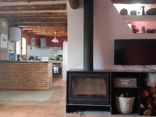 a fireplace in a living room with a tv at Casa CARMA in Campillo de Ranas