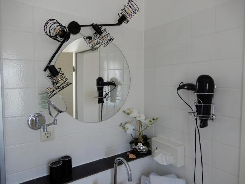 ein Bad mit einem Waschbecken, einem Spiegel und Lampen in der Unterkunft Hotel Kurallee in Meersburg