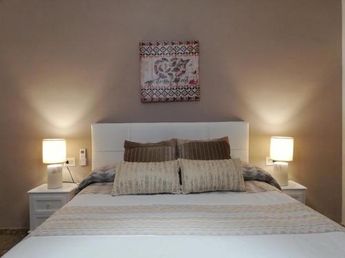 1 dormitorio con 1 cama blanca grande y 2 lámparas en Medina Baguh (VFT), en Priego de Córdoba
