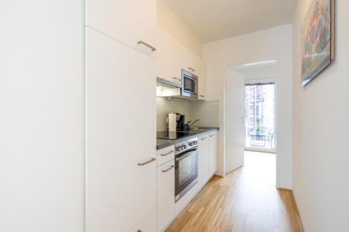 a kitchen with white cabinets and a stove at FeelGood Apartments GreenLiving | contactless check-in in Vienna